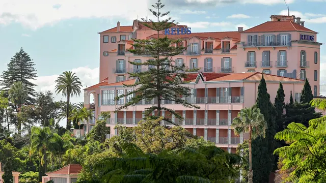 The pink facade of Reid's Palace hotel among palms above Funchal, Madeira